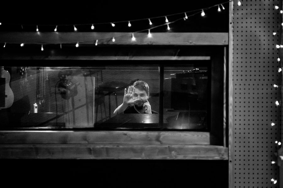 Elliot Vaughan waving through the studio control room window at night